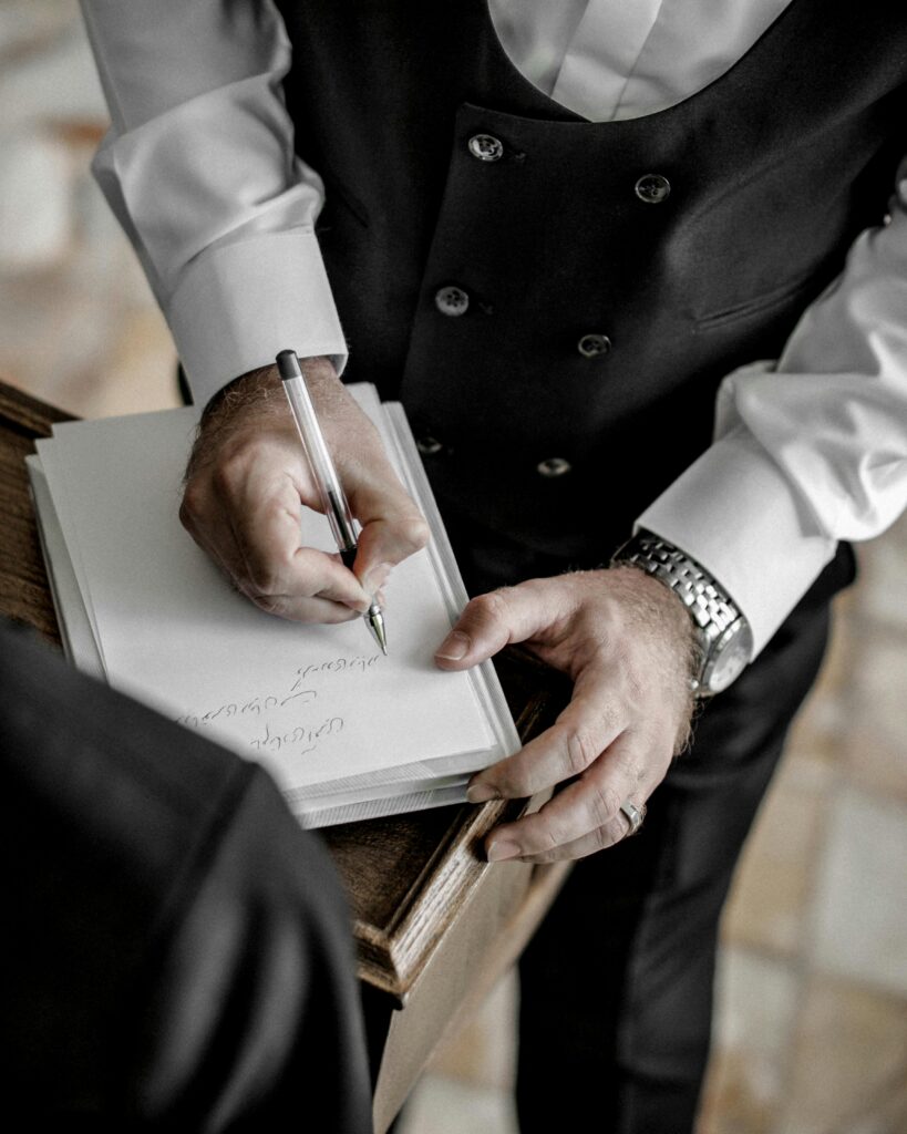 pexels-photo-3673458-3673458 Close-up of a man in formal attire signing a document during a wedding ceremony.
